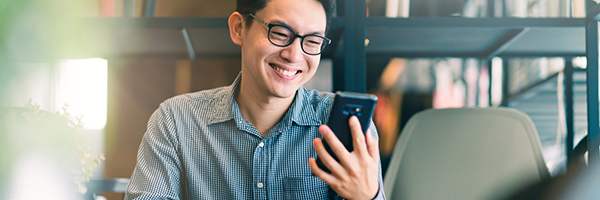 Hombre sonriendo mientras sostiene y mira un dispositivo Android.